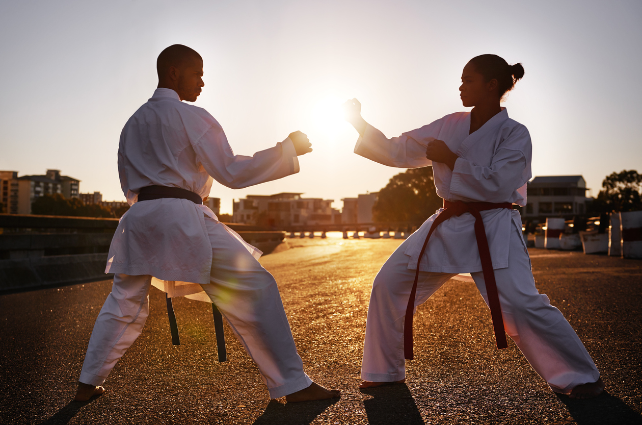 Two sportspeople facing off and practicing their karate while wearing