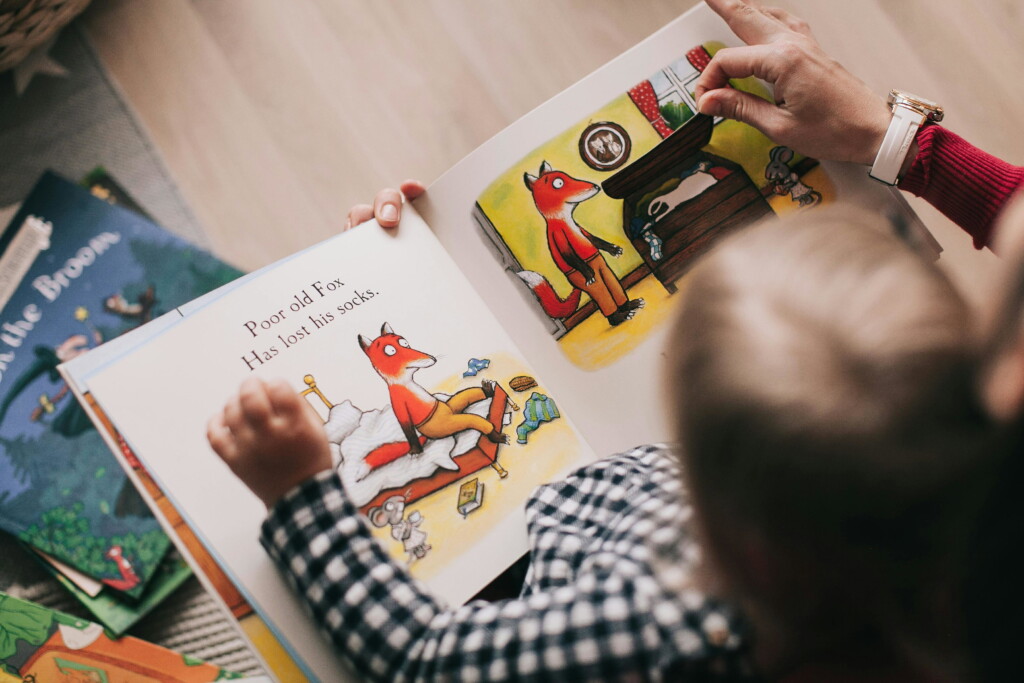 A little boy reading a book with his mother